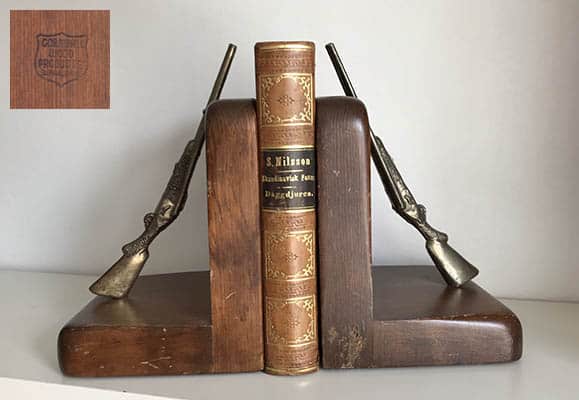 Bokstöd i trä med två gevär i metall (mässing?)