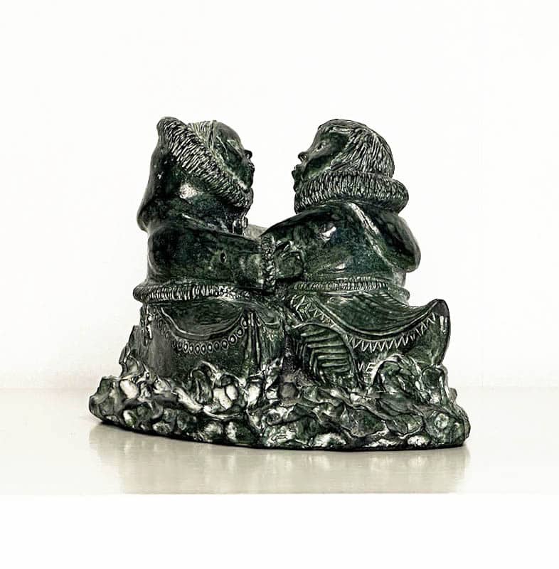 [Grönland ; Skulptur] : SKULPTUR, täljsten, inuitpar omfamnades i kajaker. Formgjuten i ett täljstensliknande (soapstone) material (turistsouvenir från andra hälften av 1900-talet)